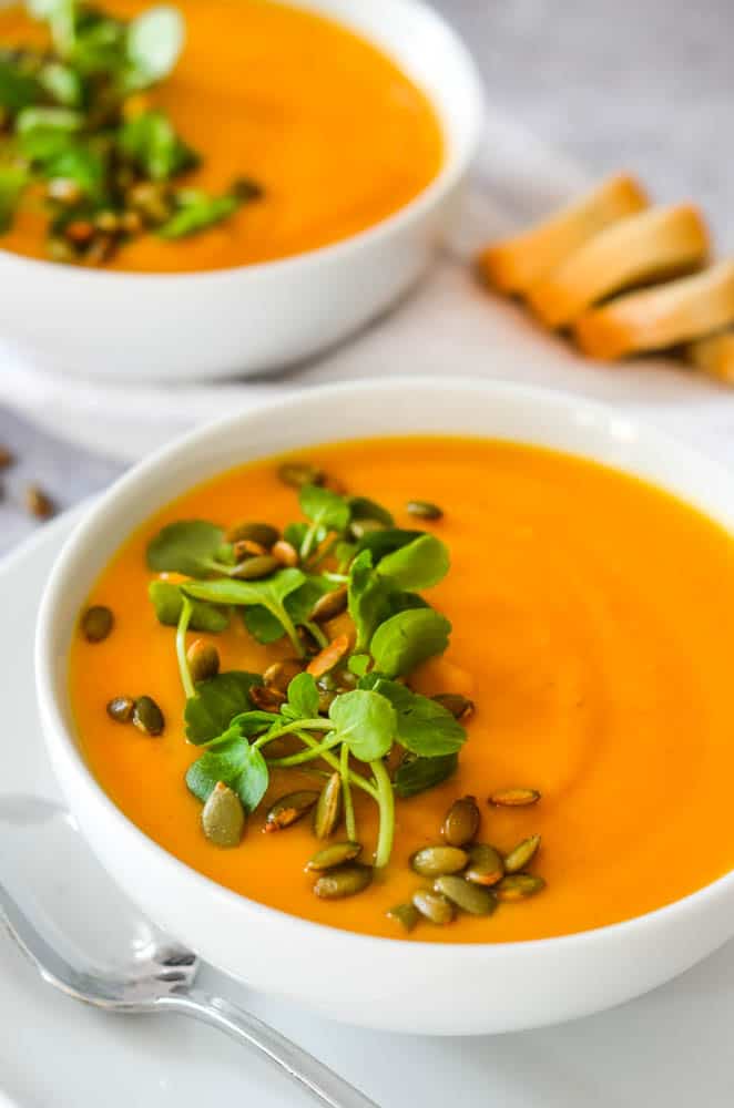 close up picture of a bowl of butternut squash soup with watercress and pepitas. 