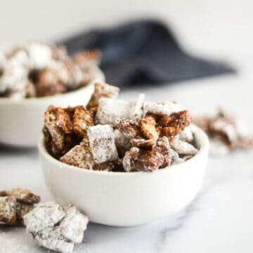 close up white bowl of puppy chow with blue napkin and another bowl in background