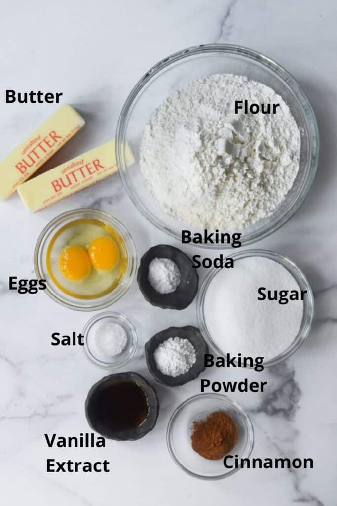 all of the ingredients needed with text labels: flour, baking soda, baking powder, sugar, cinnamon, vanilla extract, salt, eggs, and butter. 