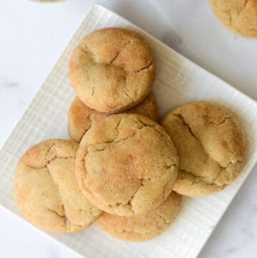 stack of snickerdoodle cookies on white square plate.