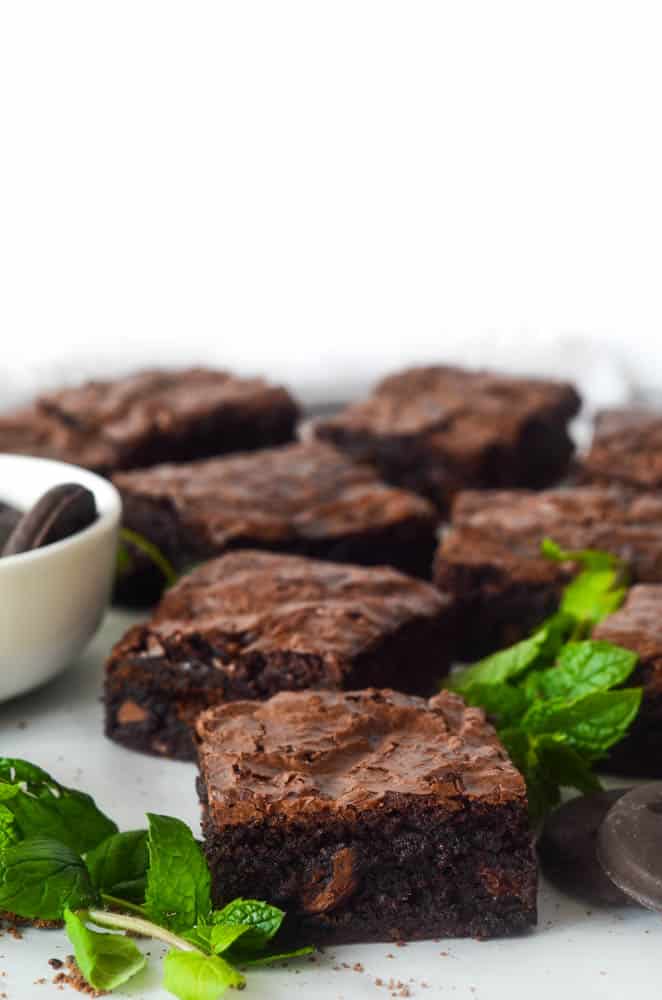 close up shot of one Thin Mint brownies square with fresh mint and other cut brownies in the background. 