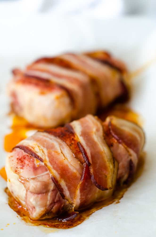 up close picture of a fully cooked bacon wrapped pork chop fresh out of the oven. 