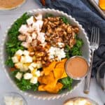 sweetgreen harvest bowl in a white scalloped bowl with sweet potatoes, apples, chicken, wild rice, almonds, and goat cheese over a bed of kale.