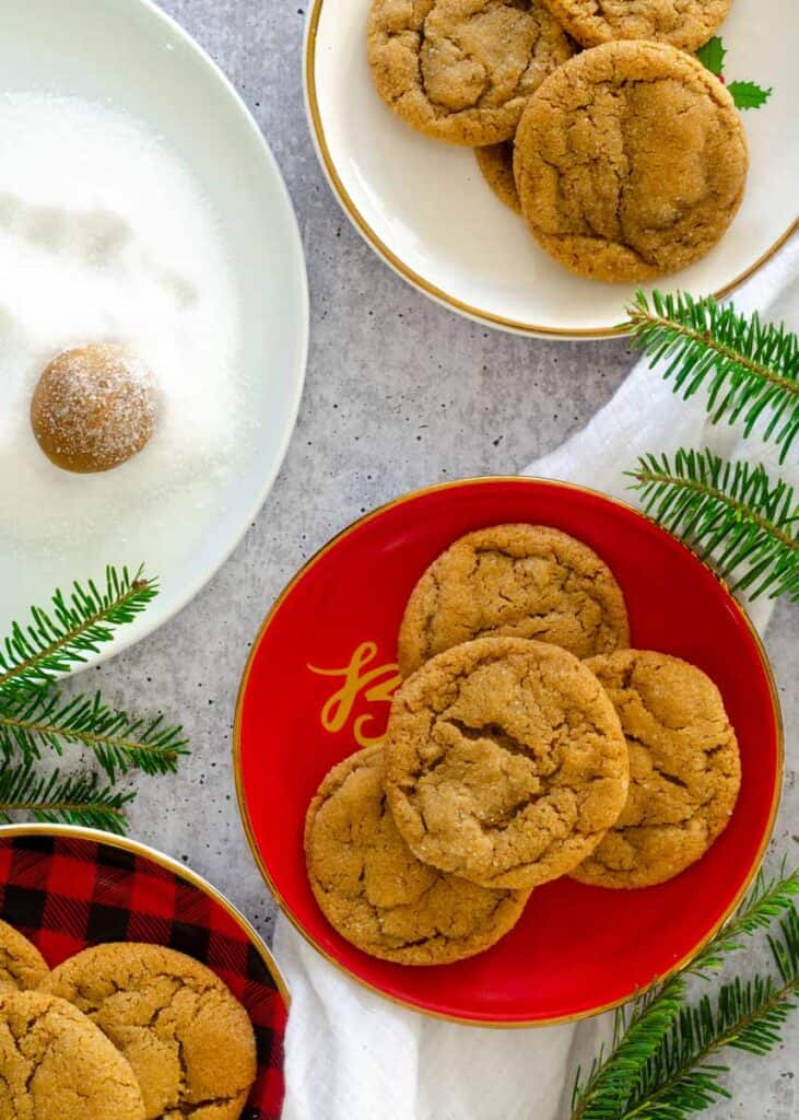 Flat lay of a bourbon ginger molasses cookie close up on top of a red plate of other ginger cookies.