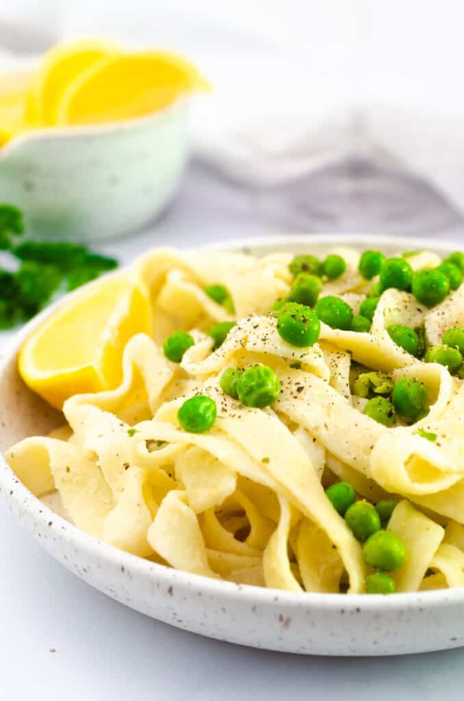 close up picture of peas on the fettuccine noodles. 