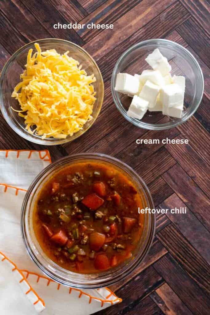 aerial shot of three bowls labeled. one has chili, one has cheese, and the other cream cheese. 