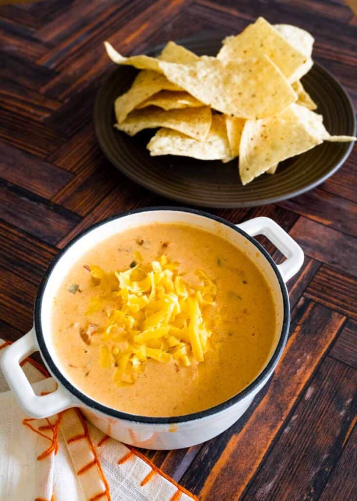 chili cheese dip in small dutch oven with plate of chips next to it. 