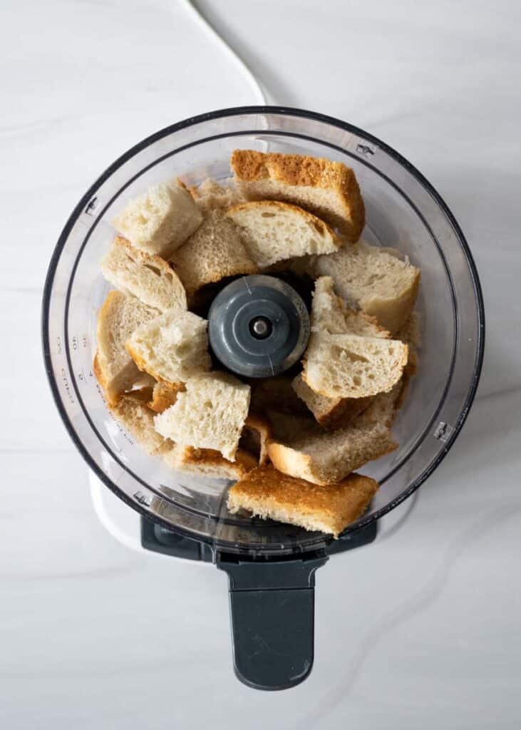 food processor bowl with cubes of bread resting in it without a lid. 