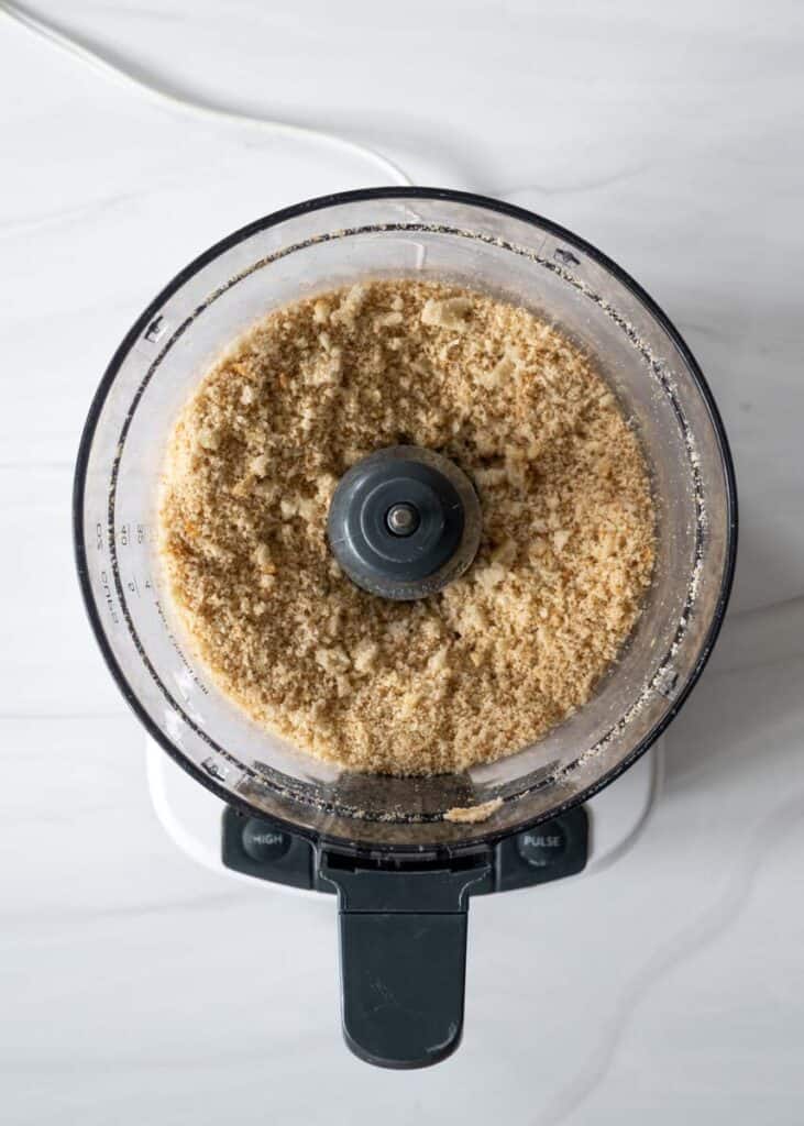 processed bread turned into breadcrumbs sitting in bowl of food processor. 
