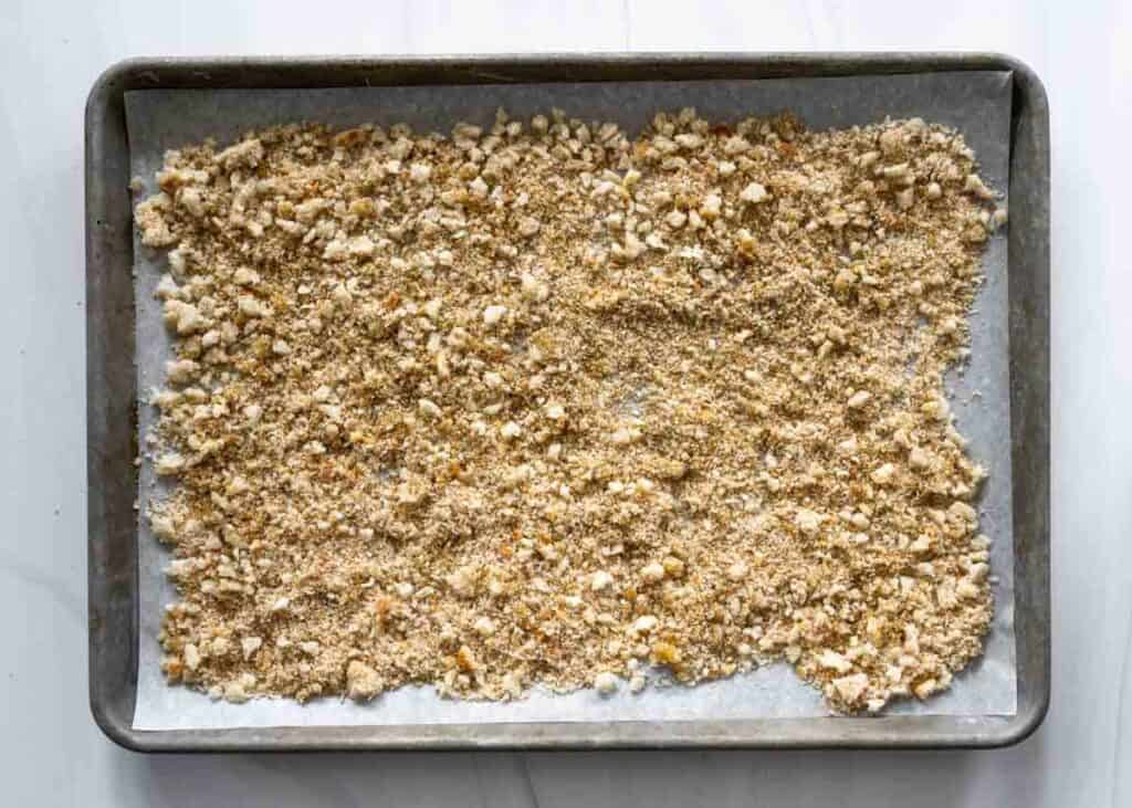 tray of breadcrumbs in a single layer on a parchment-lined baking sheet. 