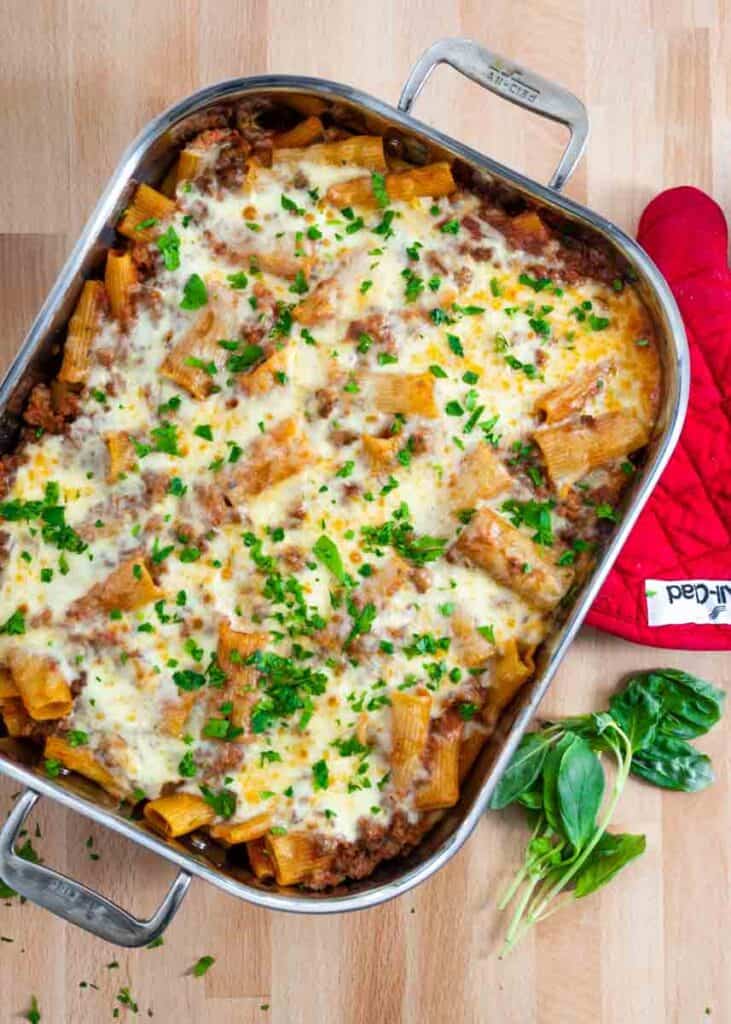 baked rigatoni in a large casserole dish with basil sprinkled on top.