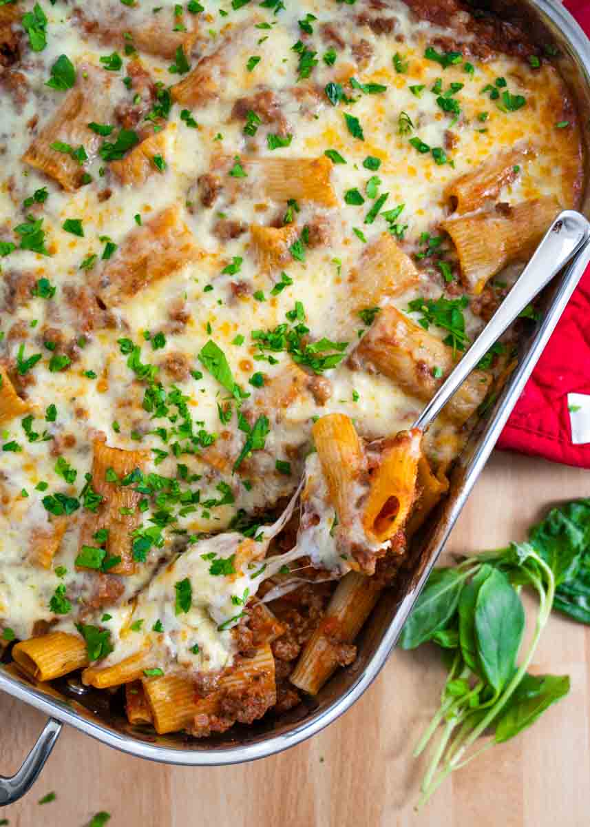 aerial photo of a spoonful of baked rigatoni on a spoon with a cheese pull. 