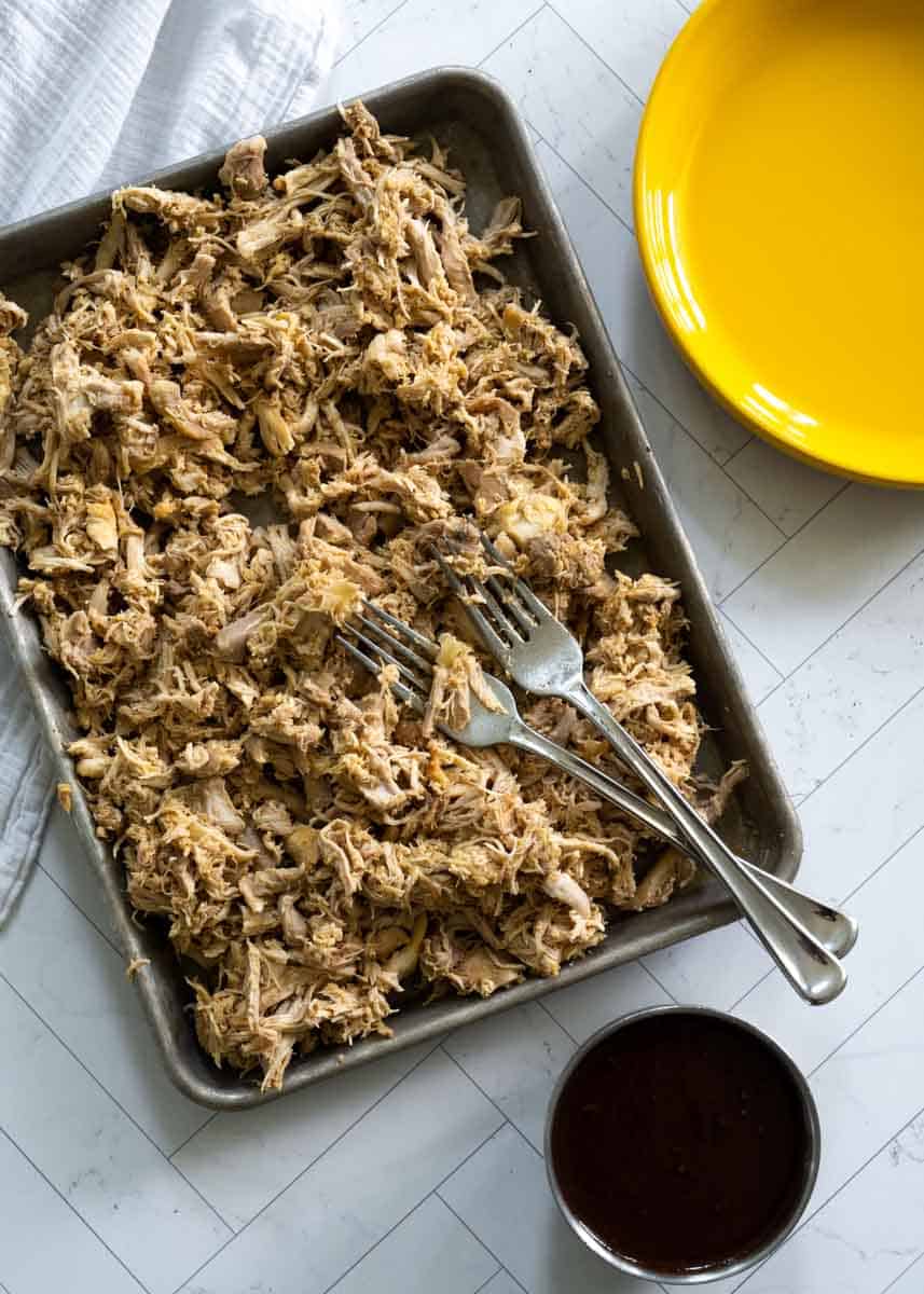 shredded chicken on a platter with two forks buried in the chicken. 
