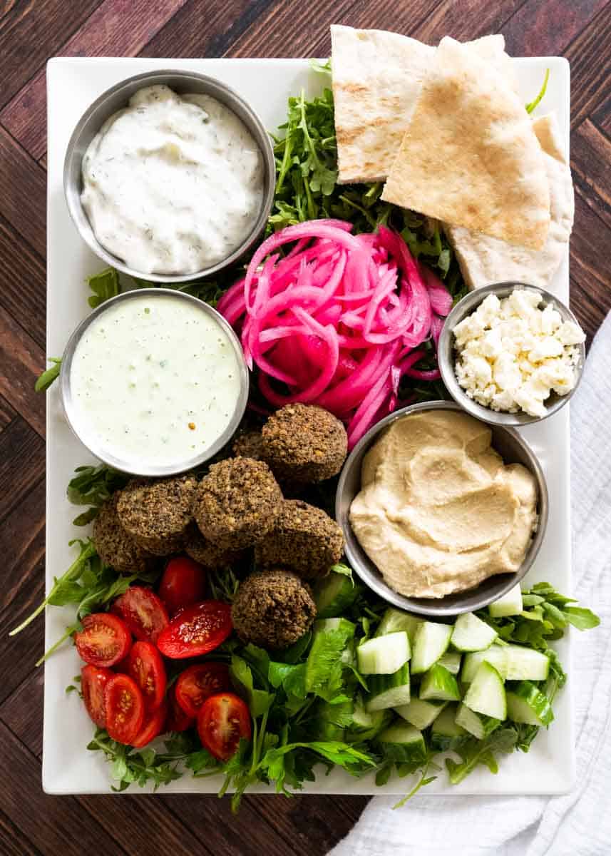 falafel platter with several ingredients on a white rectangular serving plate.