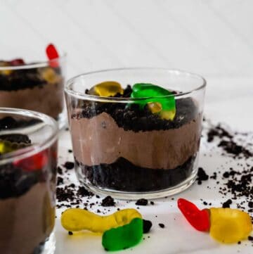 side view of Oreo pudding cups with gummy worms in a small glass cup.