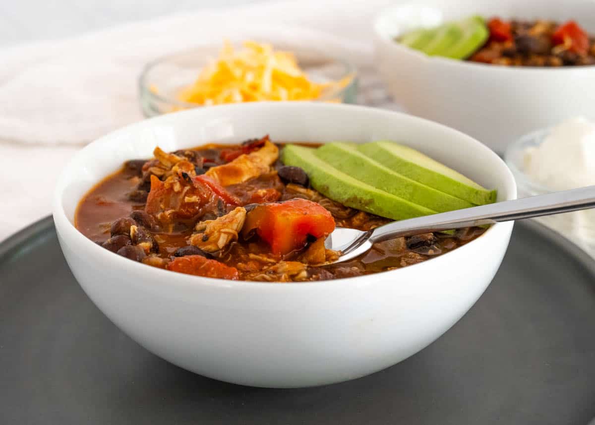 horizontal picture of a bowl of pulled chicken and black bean chili. 