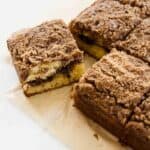 Close up of slice of coffee cake pulled away from the rest of the cake, exposing the cinnamon crumb layer in between layers of vanilla cake.