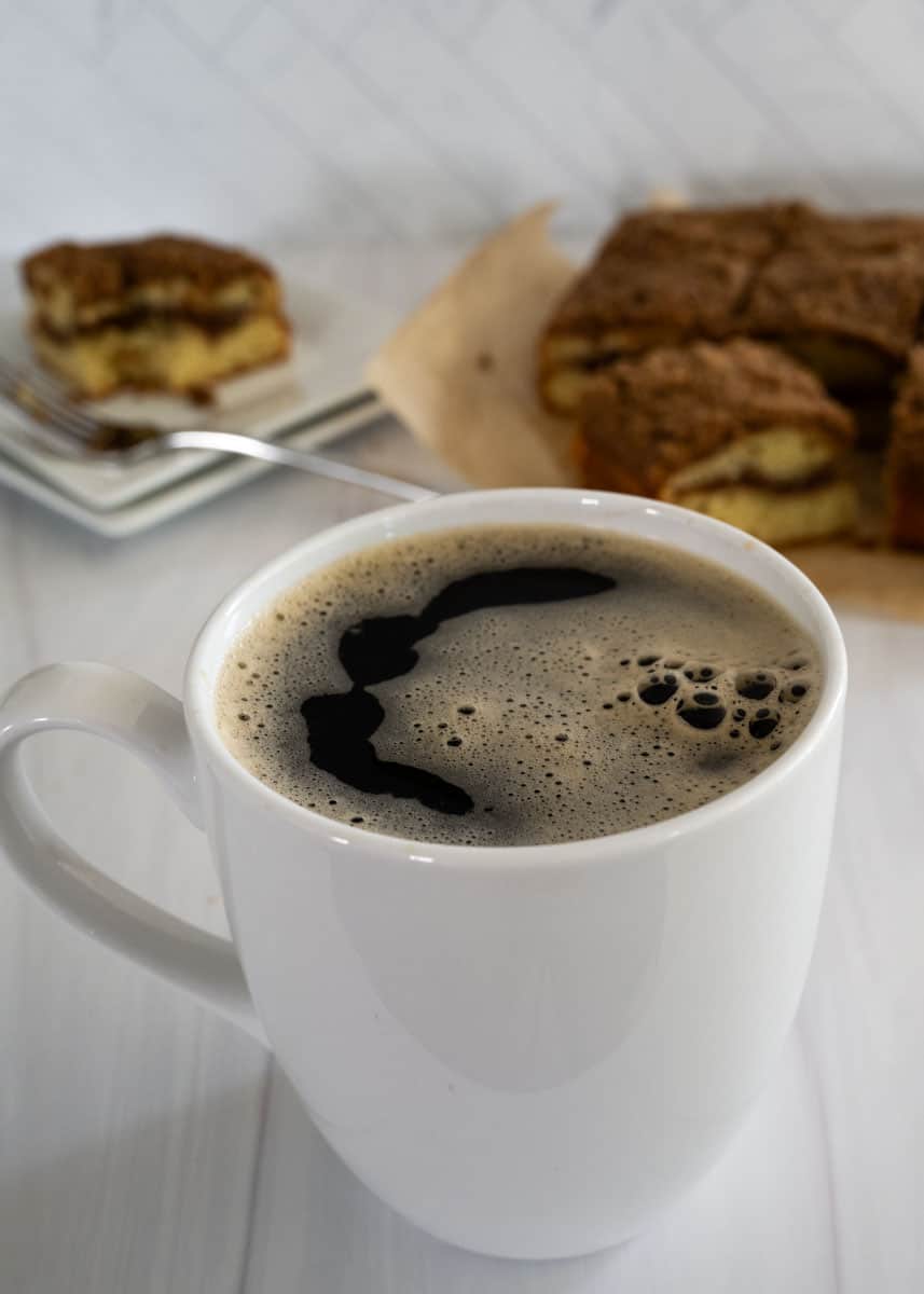 White mug with coffee in with with bubbles on top. 