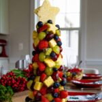 A Fruit Christmas Tree on white platter on dining room table.