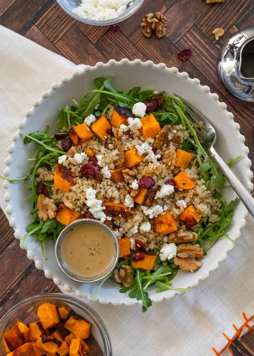 Flatlay picture of a big bowl of Pumpkin and Quinoa Salad with goat cheese, cranberries, and walnuts. 