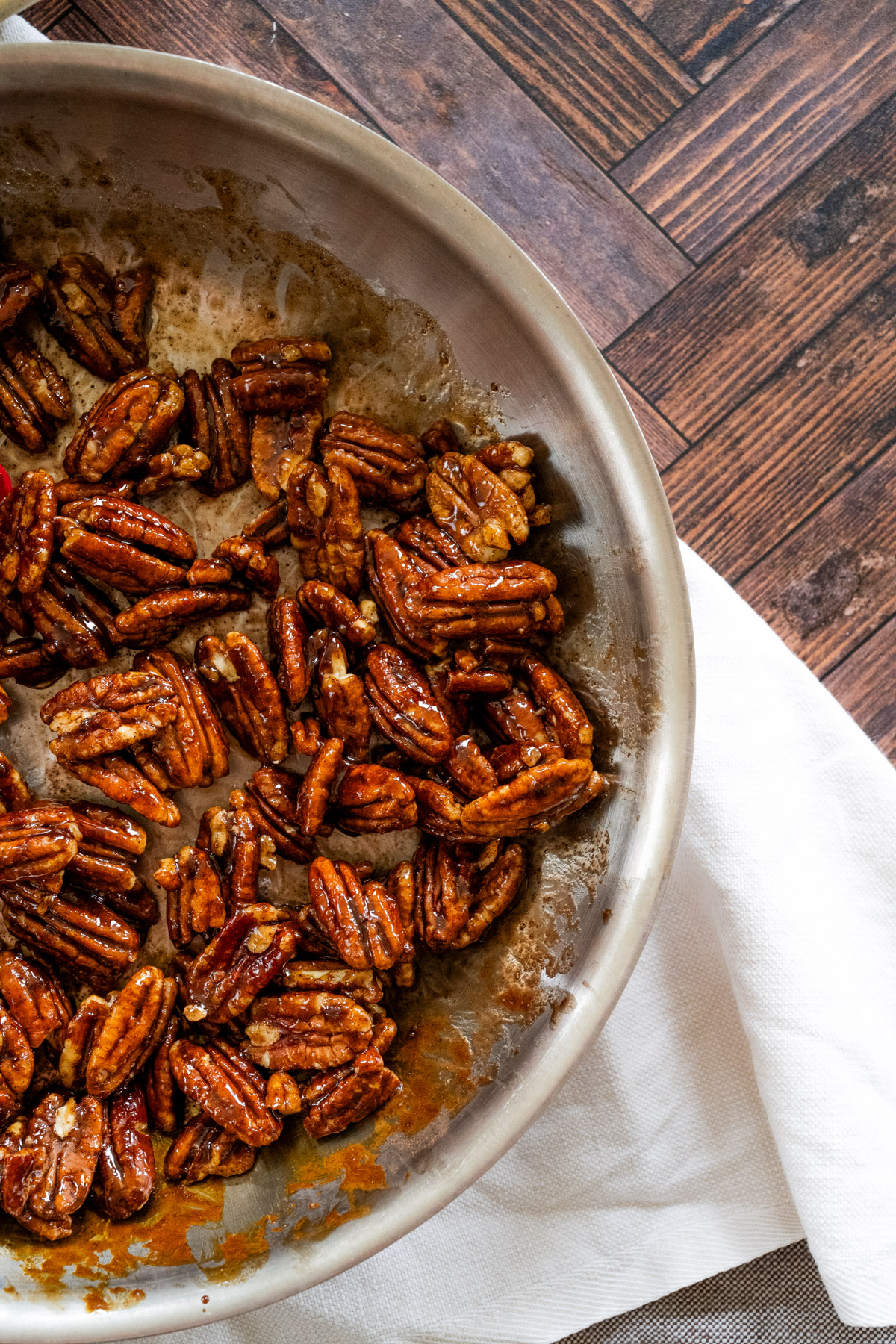 Large frying pan with candied pecans resting in the pan after being tossed with the brown sugar mixture.
