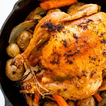 This whole roast chicken made in a cast iron skillet makes for juicy and flavorful meat with crispy crunchy skin. Potatoes, carrots, onions, and garlic are roasted with the chicken making for a complete meal in one skillet.