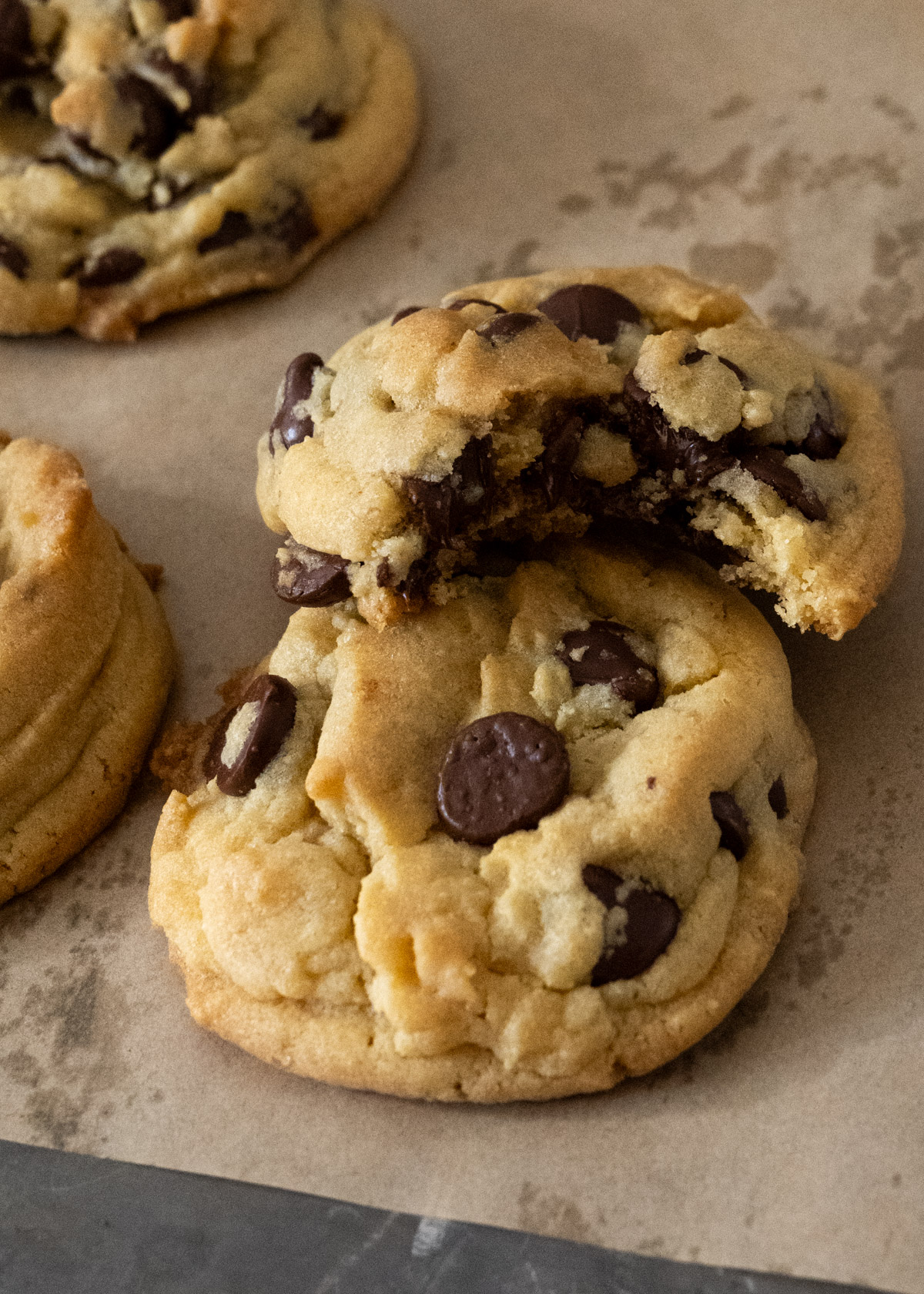 Very close picture of a chocolate chip cookie that's been bitten resting on top of another chocolate chip cookie. 