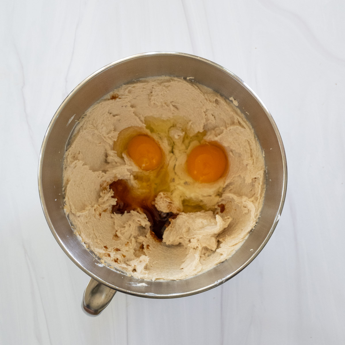 step 3 showing two eggs and vanilla extract added to the sugars. 