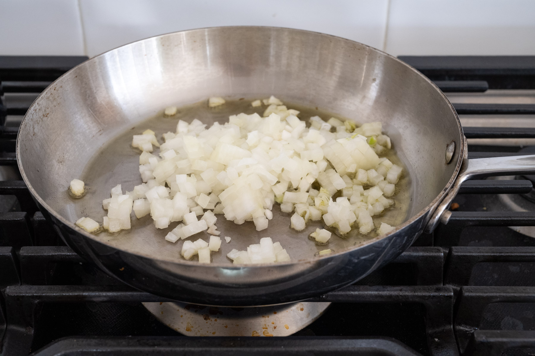Step 2 of the directions showing chopped onions added to a pan of olive oil, cooked until tender. 