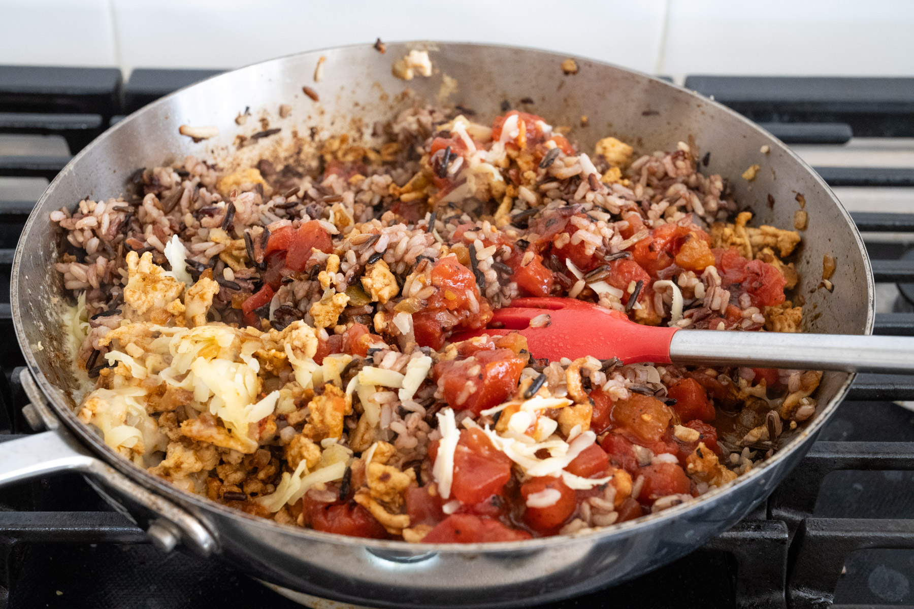Step 6 of the directions, showing cheese and diced tomatoes added to the pan. 