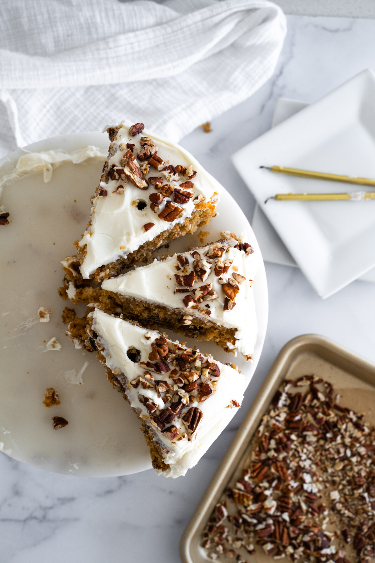 Aerial picture of the top of a carrot cake that has three slices left. 
