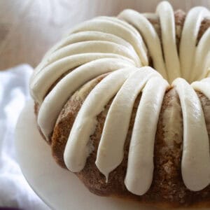 Side view of a fully frosted Bundt Cake with ribbons of cream cheese frosting just like Nothing Bundt Cakes does.