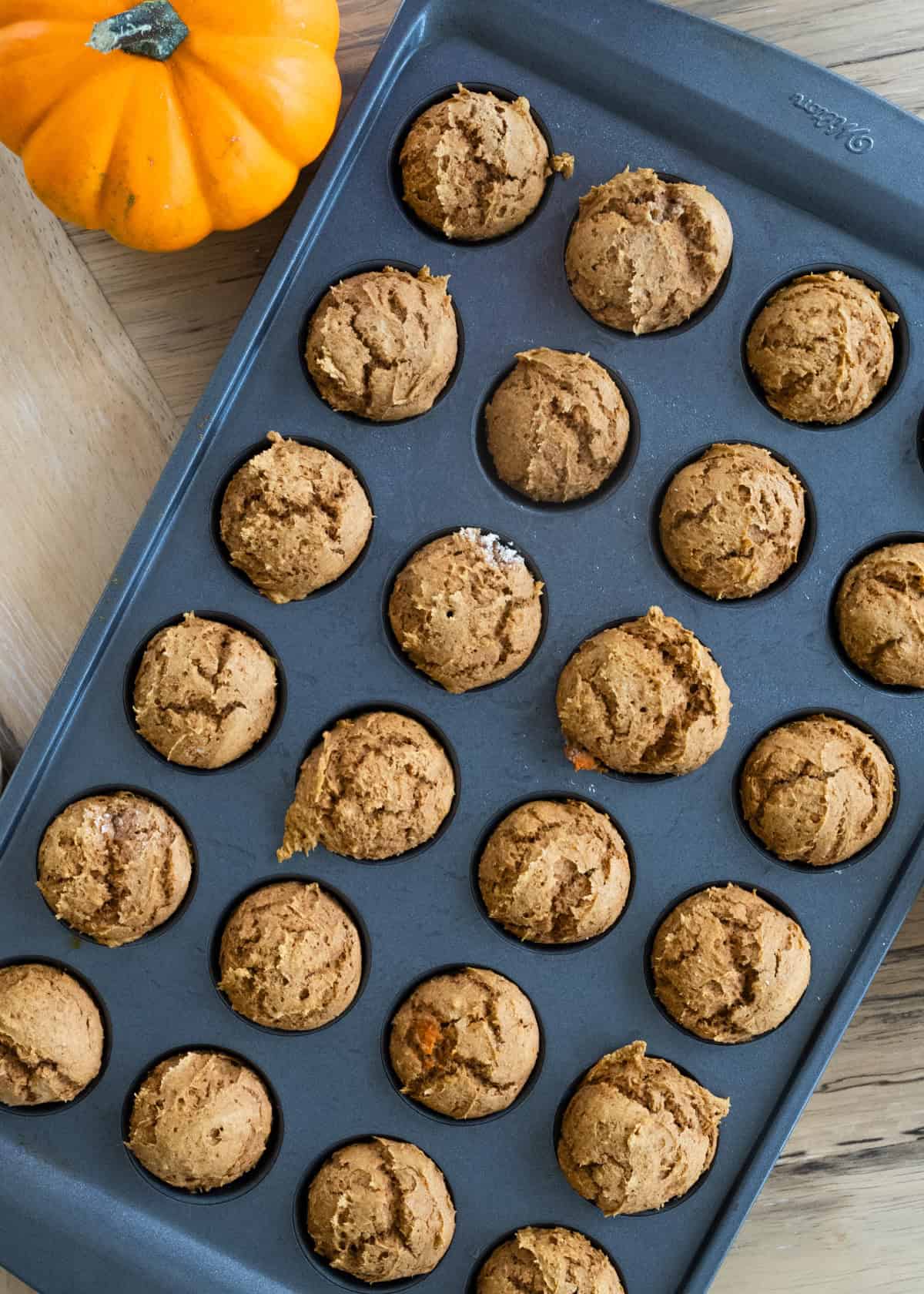 Aerial view of a mini muffin tray on a table right after the donut holes have come out of the oven.