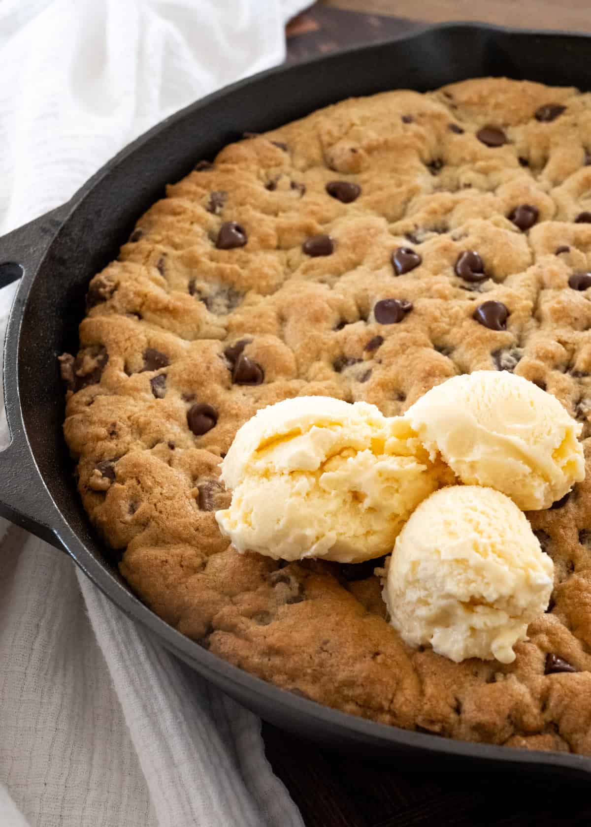 Close up picture of three scoops of ice cream on top of a pizookie (or chocolate chip skillet cookie).