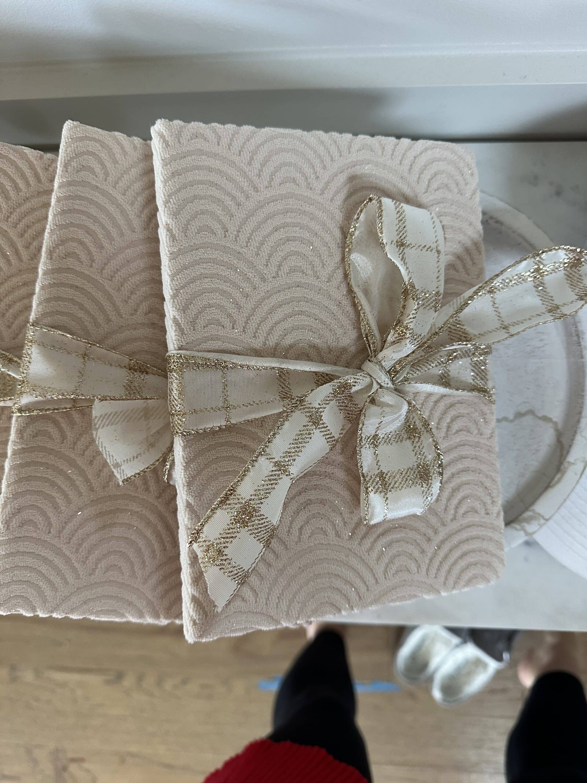 A pile of textured journals with cream and gold ribbon tied around them that were party favors.