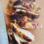 boneless skinless chicken thighs sliced on a cutting board.