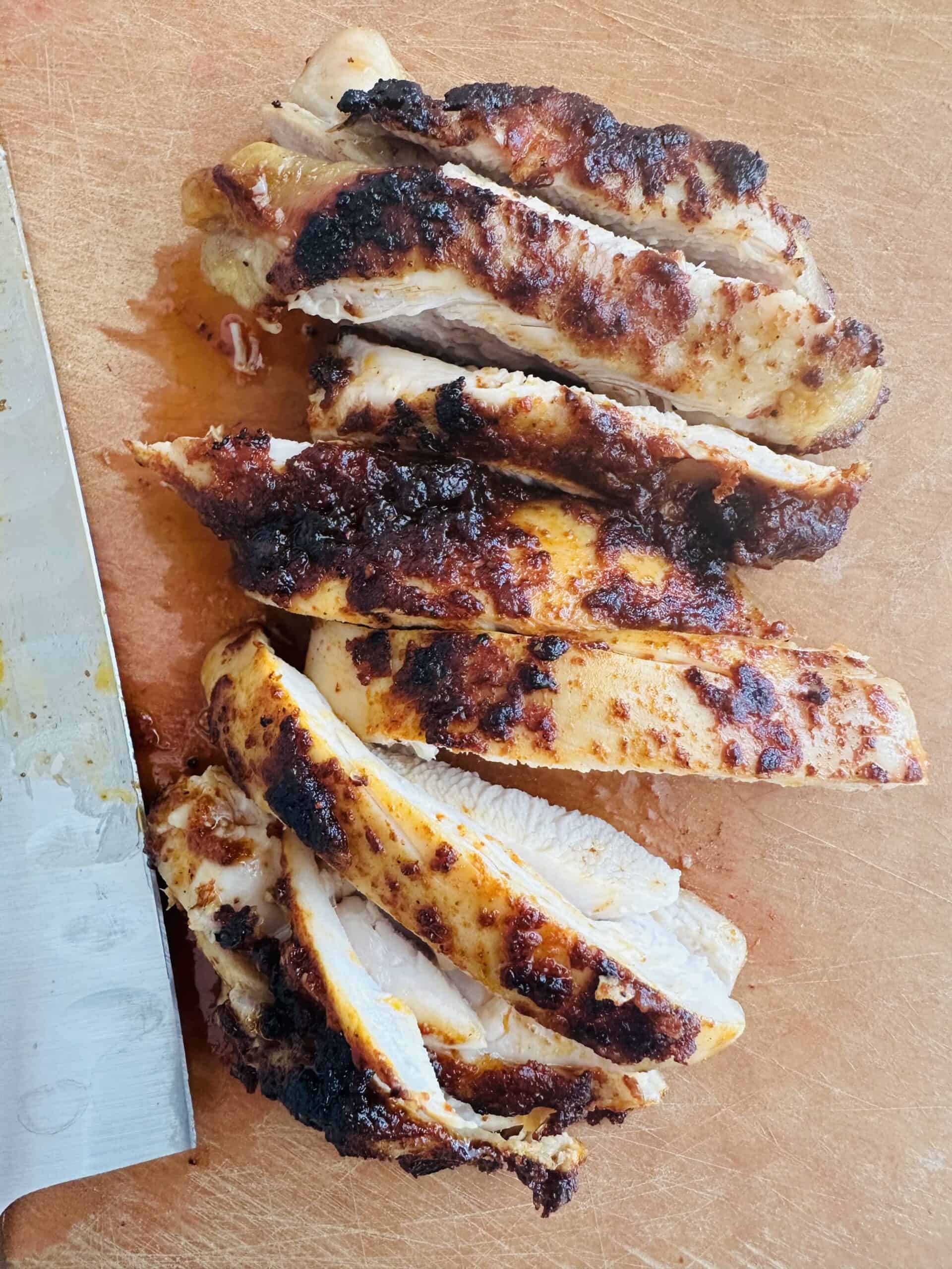 boneless skinless chicken thighs sliced on a cutting board.