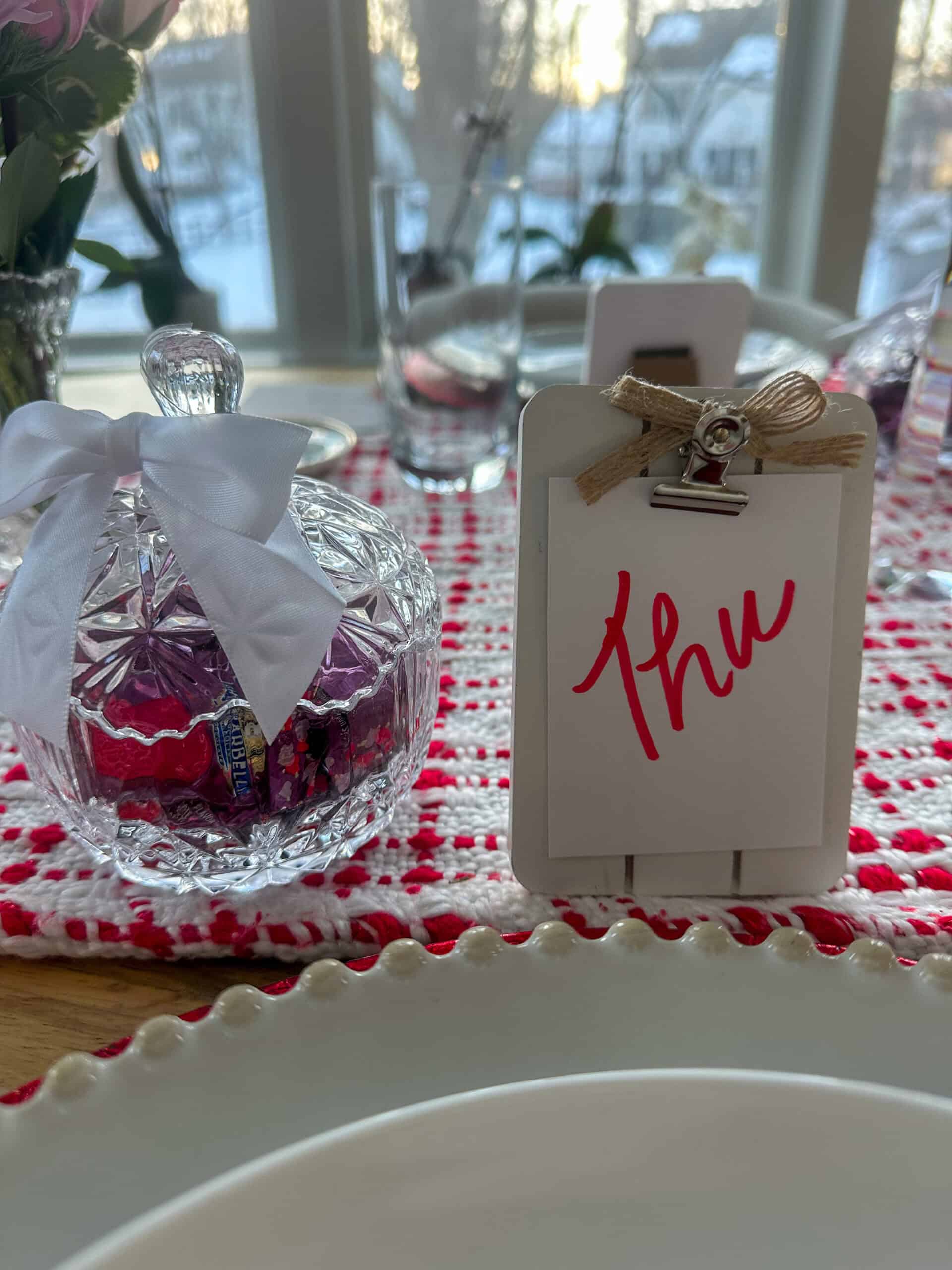 Close up picture of a glass candy jar filled with Ghirardelli chocolates that were used as party favors.