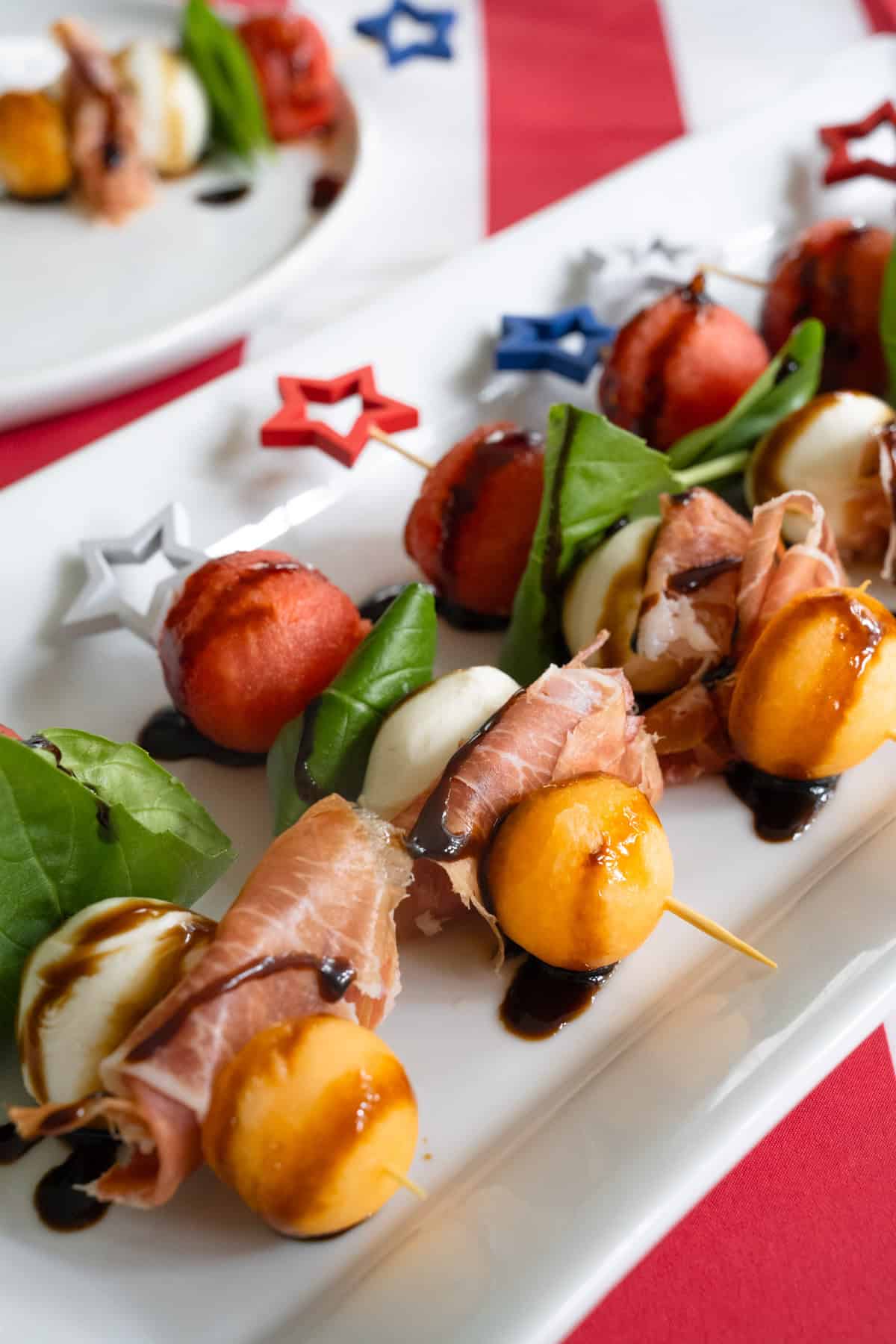 Cose up of the melon and prosciutto skewers drizzled with balsamic glaze.