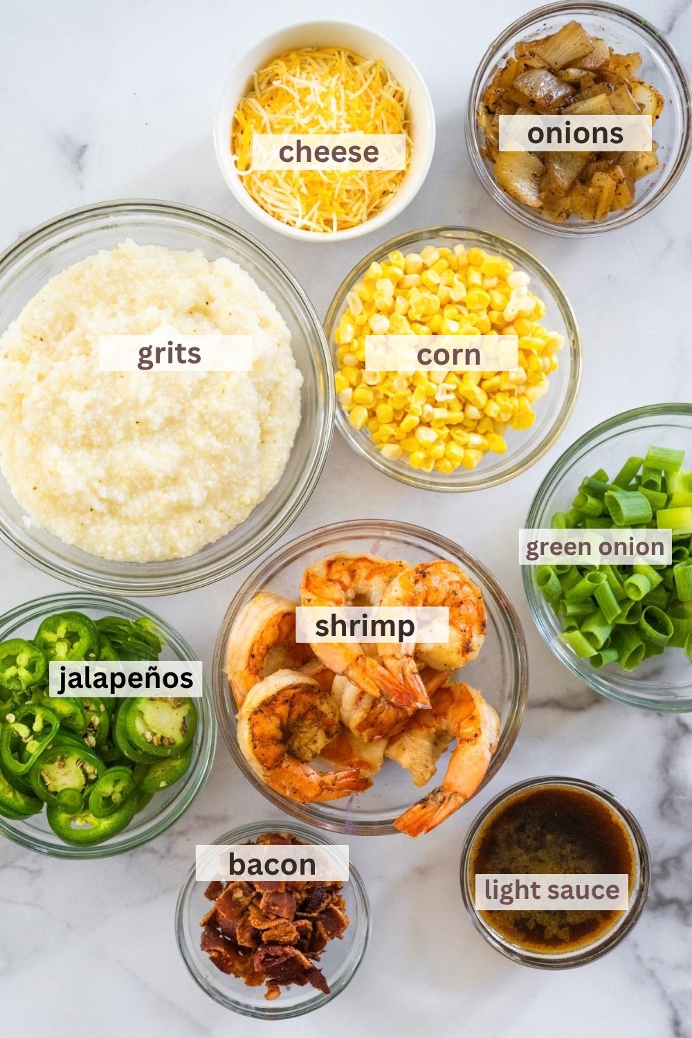 Ingredients labeled over specific bowls, including grits, cheese, onions, corn, green onion, shrimp, jalapeños, bacon, and light sauce.